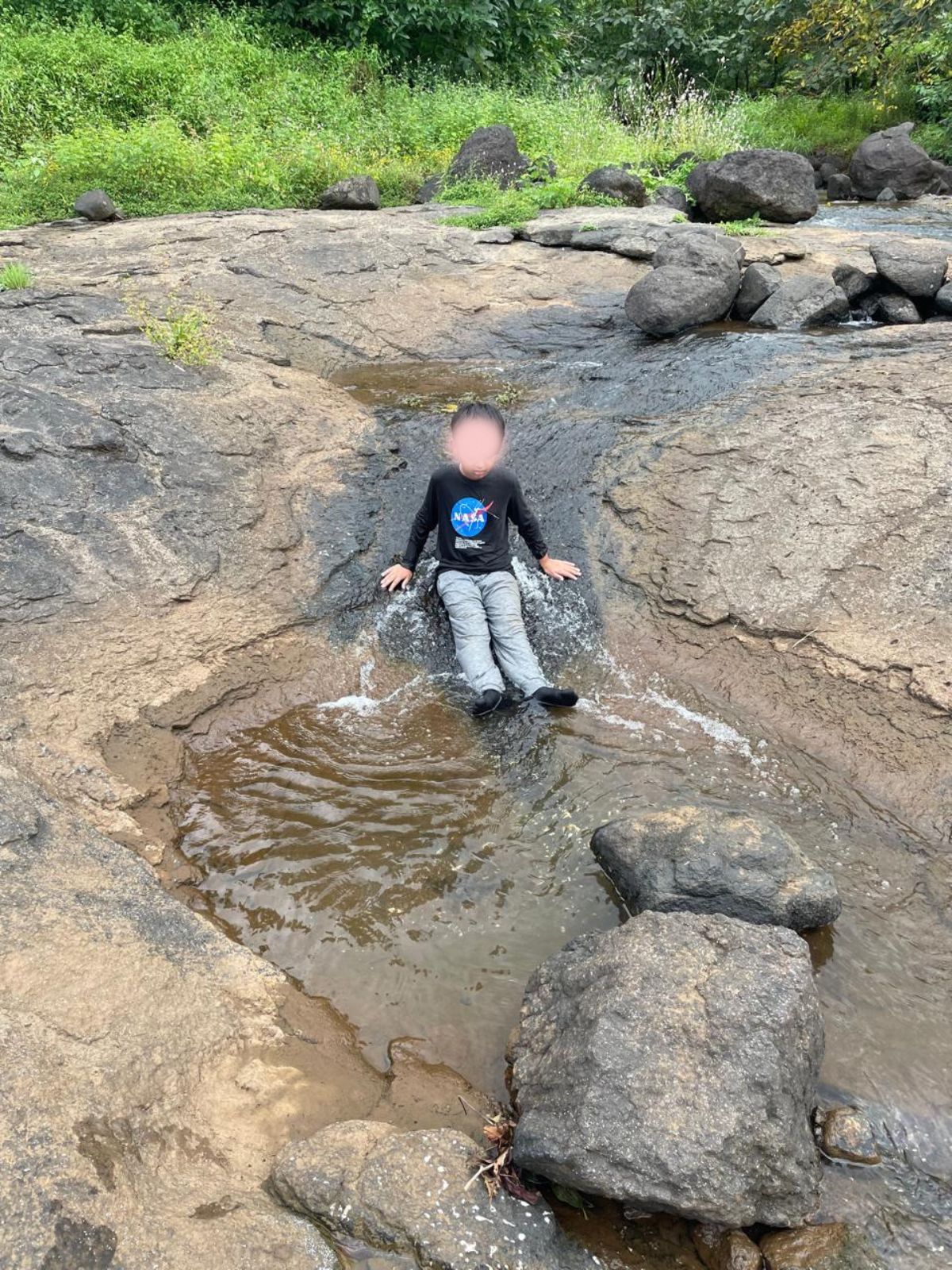 Child relaxing on rocks by a stream